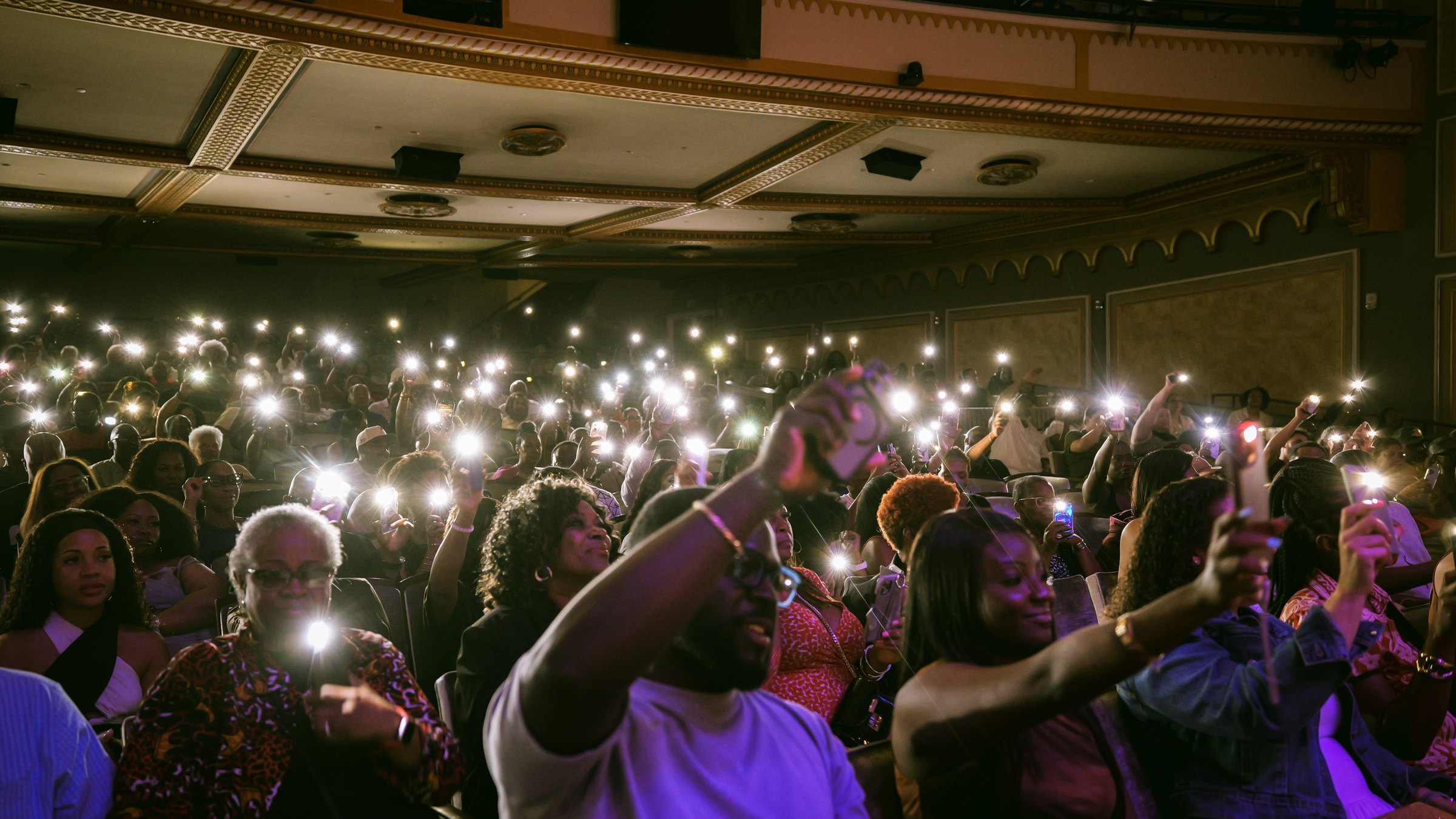 A packed Carolina Theatre with the audience holding up phone lights